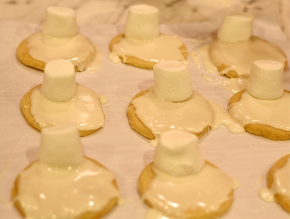 Place one marshmallow on top of each "snowman body."  Lightly press on marshmallow so it sticks to cookie icing.
